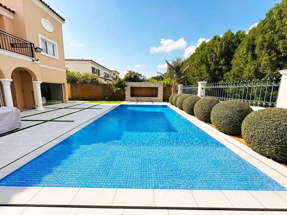 Blue swimming pool surrounded by palm trees and landscaped gardens