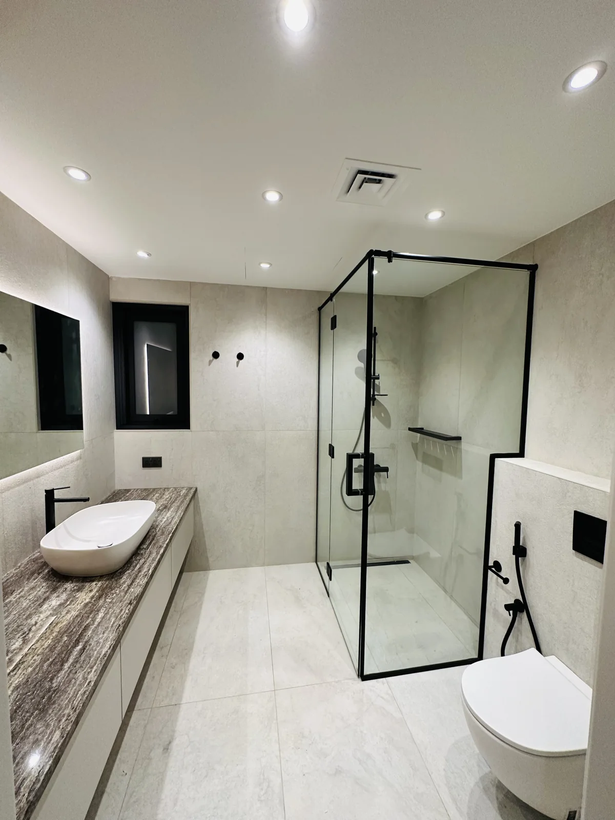 Bathroom with a glass shower enclosure, pale stone finishes and a countertop basin