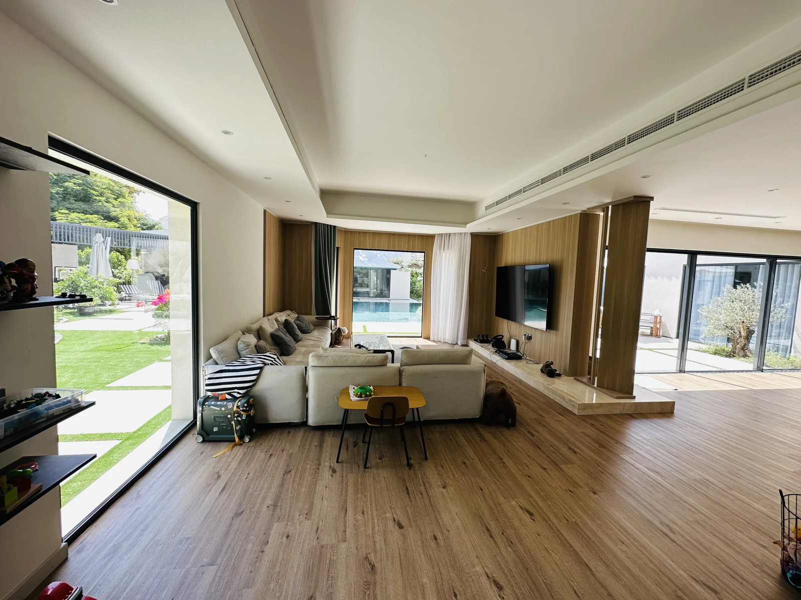 Open living room with timber flooring, wall joinery and garden views