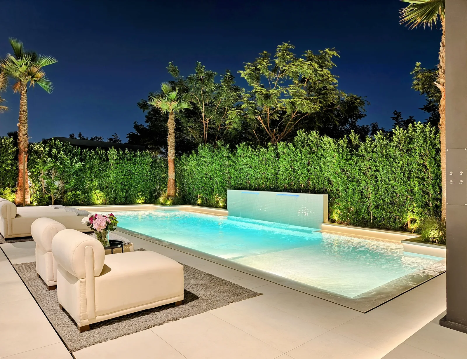 Pool, palms and outdoor seating lit for the evening