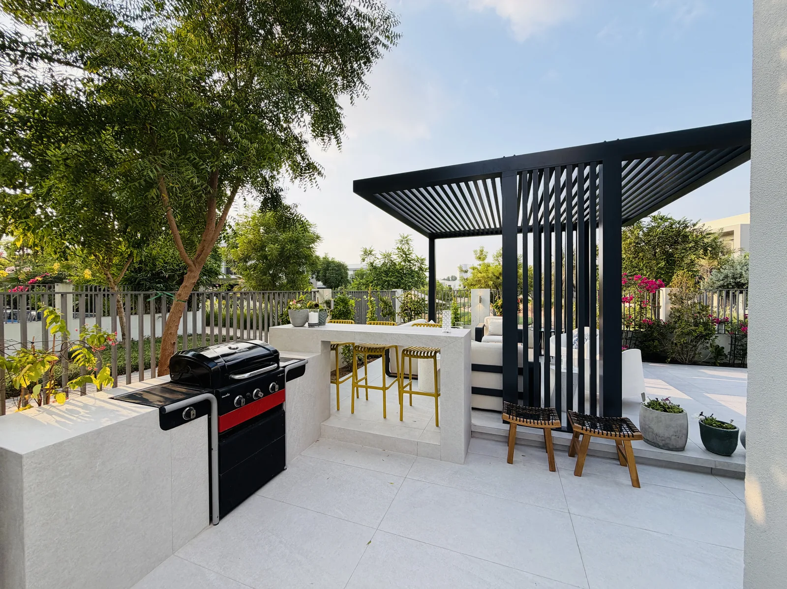 Outdoor BBQ counter and bar seating beside a landscaped garden