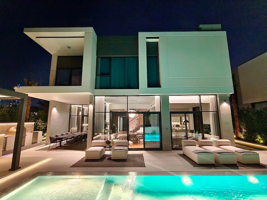 Illuminated contemporary villa and pool at dusk